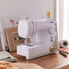 a sewing machine sitting on top of a wooden table next to a basket with flowers