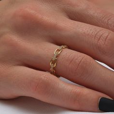 a woman's hand wearing a gold ring with diamonds on the middle of it