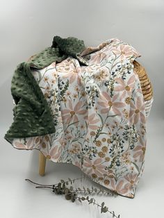 a piece of fabric with flowers and leaves on it sitting next to a wicker basket