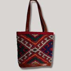 Intertwined's beautifully crafted tote bag is handmade in Morocco from locally tanned leather and vintage, handwoven kilim. Each kilim is one-of-a-kind and handwoven with unique colors and patterns based on the region where it is made. This bag combines style and function! Several of our kilim totes also coordinate with our kilim weekenders so you will truly be traveling in style! Artisan Handwoven Shoulder Bag For Shopping, Traditional Top Handle Bag With Leather Handles, Traditional Red Bags With Leather Handles, Traditional Brown Tote Bag, Brown Woven Bag For Daily Use, Brown Weaving Bag For Daily Use, Brown Woven Bags For Daily Use, Brown Weaving Bags For Daily Use, Bohemian Weaving Bags For Shopping