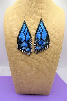 a mannequin with blue and black beaded butterfly earrings on top of it