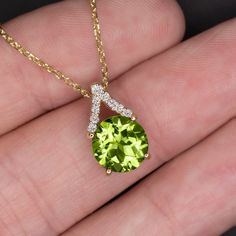 This elegant peridot and diamond pendant features a bright green peridot set beneath a glittering V of vibrant pave set diamonds. The vivid chartreuse of the peridot pops beautifully against the bright white of the diamonds. The pointed bail creates a subtle geometric look that gives this pendant a modern edge while still maintaining a sophisticated and timeless aesthetic. This pendant will add a bright pop of color to your wardrobe! The 8mm peridot center is a gorgeous and well saturated yellow Fine Jewelry Lime Green Diamond, Fine Jewelry With Lime Green Diamond, Green Diamond Round Cut Necklaces, Green Round Cut Diamond Necklace, Green Gemstone Round Cut Necklace, Green Gemstone Necklace With Round Cut, Round Cut Peridot Jewelry In Yellow Gold, Fine Jewelry Peridot Necklace For Anniversary, Peridot Color