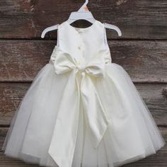 a dress hanging on a wooden wall with a white bow at the waist and neckline