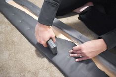 a person using a remote control to measure the length of a piece of furniture