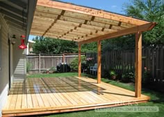 a wooden deck in the middle of a yard with a pergolated area on it