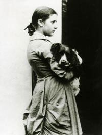 an old black and white photo of a young woman holding a dog in her arms