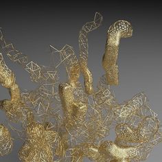 an abstract gold sculpture is shown on a gray background