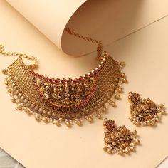 Description This statement choker necklace is an exclusive inclusion to our antique collection- traditional gold jewelry carved with Laxmi motifs and ivy design along with pearl & gold drop beads. Styled with simple yet gorgeous floral motifs and geometric patterns this is ideal for wedding events or festive occasions. Details & Specifications: Materials used : Brass Alloy with Antique Gold Plating Weight – Choker 180 gm, Earrings 45.86 gm Length – Choker 24.5 cm, Earrings 6.5 cm Make it custom Bridal Choker Necklace With Intricate Design For Festive Occasions, Festive Bridal Choker Necklace With Intricate Design, Festive Bridal Choker With Intricate Design, Festive Temple Choker Necklace For Celebration, Festive Celebration Temple Choker Necklace, Festive Intricate Design Choker Necklace, Festive Temple Necklace With Intricate Design Choker, Festive Intricate Temple Necklace Choker, Festive Intricate Design Temple Choker