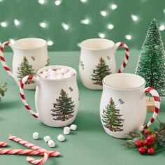 three christmas mugs with candy canes in front of them on a green surface