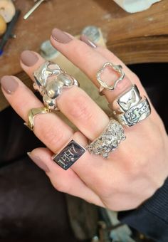 a woman's hand with five different rings on it and one has a cat