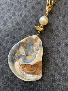 One of a kind handmade Oyster & Pearl Shell Necklace. An assemblage of pretty beads top this patterned oyster shell pendant: 12mm Pearl bead, faceted gold hematite bead and a chunky gold quartz nugget are all strung together on an 18K gold plated chunky paper clip style chain. The genuine oyster seashell has two unique sides: a beautiful natural pattern in grey, gold and white with a matte ribbed texture. The glossy reverse side is hand gilded with metallic gold paint and sparkling natural pearl Gold Abalone Shell Necklace In Unique Style, Unique Gold Abalone Shell Necklaces, Unique Gold Abalone Shell Necklace, Unique Gold Necklace With Abalone Shell, Gold Abalone Shell Pendant Jewelry, Unique Gold Jewelry With Abalone Shell, Handmade Gold Jewelry With Abalone Shell, Gold Beaded Shell, Unique Gold Shell Necklaces