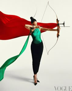 a woman in a green dress holding a bow and arrow