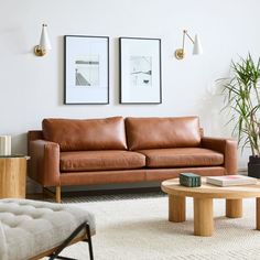 a living room with two pictures on the wall and a leather couch in front of it