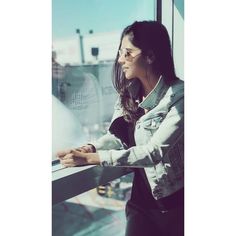 a woman leaning against a window looking out at the city