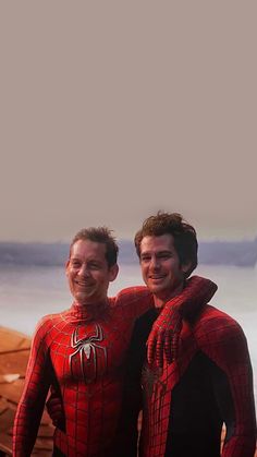 two men in spider - man suits standing next to each other