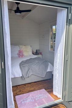 a bed sitting inside of a bedroom on top of a wooden floor next to a window