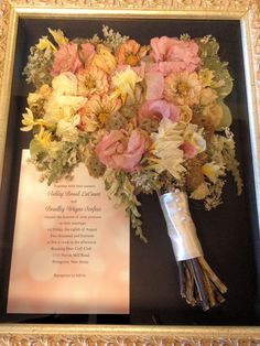 a bouquet of flowers sitting on top of a framed piece of paper next to a wedding program