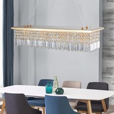 a chandelier hanging over a dining room table with chairs and vases on it