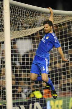 a soccer player is jumping up to catch the ball in front of his goalie