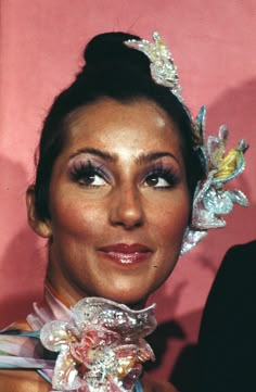 a woman wearing a tiara with flowers on her head and hair in buns