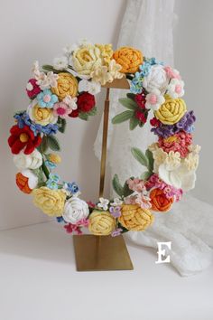 a crocheted wreath with flowers on a stand