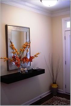 a vase filled with flowers sitting on top of a shelf next to a mirror and door