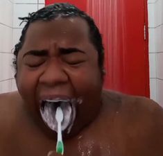 a man brushing his teeth with an electric toothbrush in front of him and red door