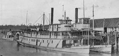 an old photo of a large boat docked at a dock with other boats in the water