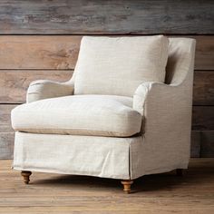 an upholstered chair in front of a wooden wall with planks on the floor