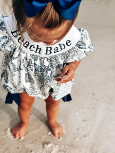 Beautiful and classic smocked bubble! In the cutest beach babe print of our original design! 🐚 wording - BEACH BABE in the smocking and navy bows on the thighs. This absolutely precious outfit is sure to be a southern staple in your little girls closet! Playful Printed Bubble Romper For Beach, Playful Printed Bubble Romper For The Beach, Blue Summer Bubble Romper For The Beach, Blue Summer Bubble Romper For Beach, Playful Short Sleeve Bubble Romper For The Beach, Playful Short Sleeve Bubble Romper For Beach, White Summer Bubble Romper For Beach, Playful Short Sleeve Beach Bubble Romper, Playful Summer Smocked Dress With Smocked Cuffs