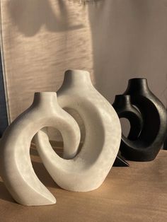 three white and black vases sitting on top of a table