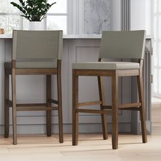 two stools sitting next to each other in front of a counter with a potted plant on it