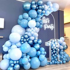 blue and white balloons are arranged in the shape of an arch for a birthday party