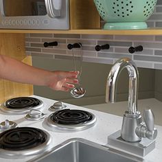 a woman is pouring water from a faucet into a kitchen sink with two burners