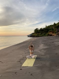 a woman is doing yoga on the beach