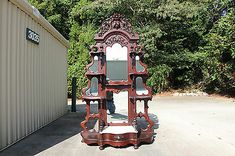 an old wooden mirror sitting in the middle of a parking lot next to a building