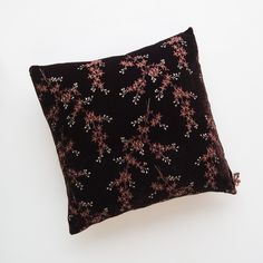 a black pillow with pink flowers on it