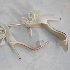 two pairs of white shoes with bows on the toes and heels are laying on top of each other