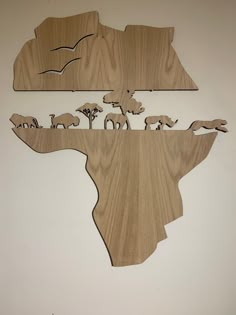 a wooden cut out of the shape of africa with elephants and giraffes