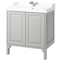 a white bathroom sink sitting under a faucet on top of a cabinet next to a mirror