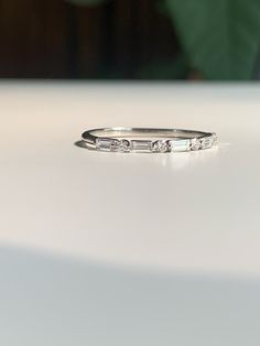 a white gold wedding band with three baguettes set in the middle, sitting on a table