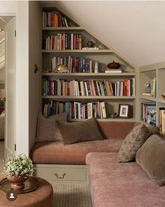 a living room filled with lots of books on top of a book shelf next to a couch