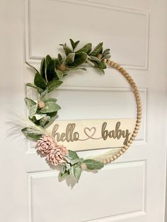 a wreath with the word hello baby hanging from it's side on a door