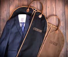 a suit case and tie bag sitting on top of a wooden floor