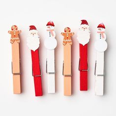 five wooden clothes pins with santa claus and snowmen on them, lined up in a row