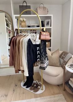 a clothing rack with shoes and handbags on it in a room filled with furniture