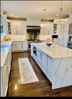 a large kitchen with white cabinets and marble counter tops, an island in the middle