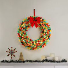 a christmas wreath hanging on the wall next to a fire place with candles and decorations