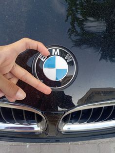 a person pointing at the bmw emblem on their car