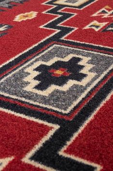 a red rug with black and white designs on the bottom is shown in close up